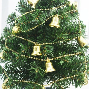 Detail einer 2m goldenen Perlenkette mit Glocken um einen grünen Weihnachtsbaum