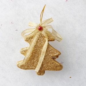 Detail of golden glitter Christmas tree ornament with a red bead and silk ribbon bow