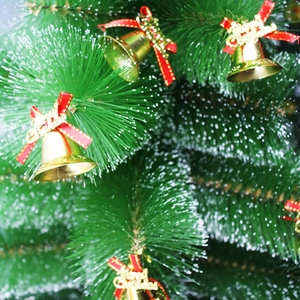Detail von goldenen Weihnachtsklingeln mit roten Schleifen auf einem grünen Tannenbaum