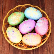 Colorful Easter eggs with floral prints and glitter inside a small yellow basket