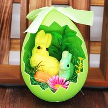 Detail view of a green Easter egg ornament with velvet bow and bunny figurines inside