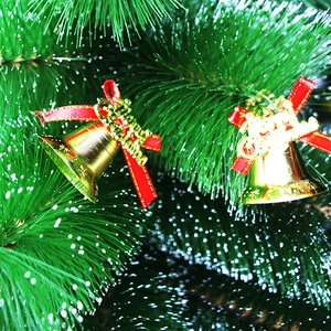 Golden Christmas bell ornaments with red velvet bows and Merry Christmas signs on a tree