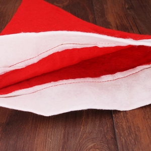 Classic red felt Christmas hat with plush white trim detail on a dark rustic wooden background