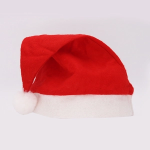 Close-up of a classic red non-woven Christmas hat with white plush pompom and trim