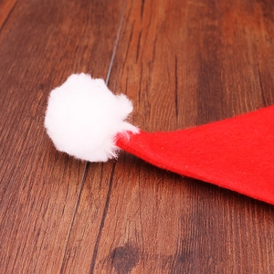 Close-up of a festive red non-woven Christmas hat with a soft white plush pom-pom ball