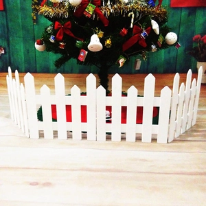White picket fence used as a decorative Christmas tree base on a light wood floor