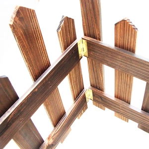 Detail of dark brown carbonized wood fence with golden metal hinges for folding
