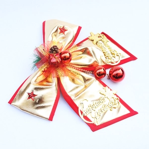 Detail of a large gold and red Christmas bow with pine cones and Merry Christmas sign