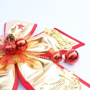Macro detail of large Christmas bow with gold fabric, red ornaments, and pine cones