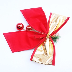 Detail of a large red and gold Christmas bow with red ornaments and pine needles