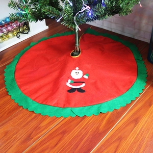 Detail of red Christmas tree skirt with green scalloped edges and Santa Claus applique