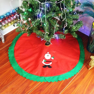 Detail of red Christmas tree skirt with green scalloped edges and Santa Claus applique