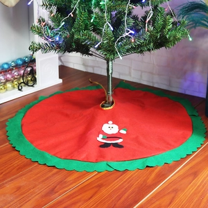 Detail of red Christmas tree skirt with Santa Claus applique and green wavy edges