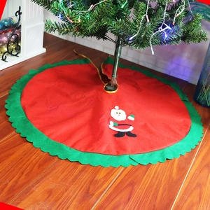 Detail of red Christmas tree skirt featuring Santa Claus applique and green scalloped edge