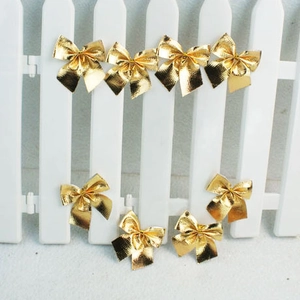 Set of eight metallic gold Christmas bows displayed on a white fence for festive decor