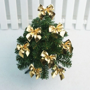 Close-up of 5cm shiny gold glitter bows hanging on a green Christmas tree branch