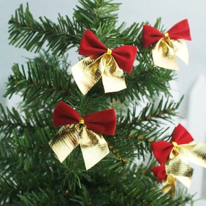 Detail of red and gold festive bows hanging on green Christmas tree branches