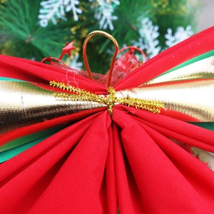 Macro detail of red and gold Christmas bow with textured fabric on pine needles