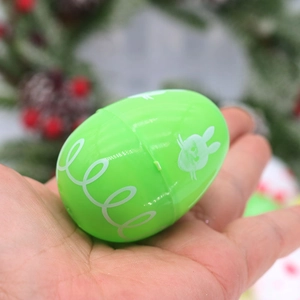 Hand holding green Easter egg with bunny pattern against a festive wreath background