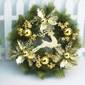Detail view of golden reindeer ornament and glitter berries on green pine wreath