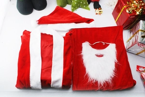 Costume de Père Noël exposé à plat avec veste en velours rouge, pantalon, bonnet et barbe