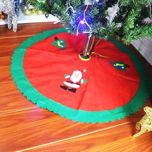 Detail of red Christmas tree skirt with Santa Claus applique on a wooden floor