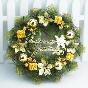 Close-up of green pine wreath with gold balls and Christmas Greetings sign on white fence