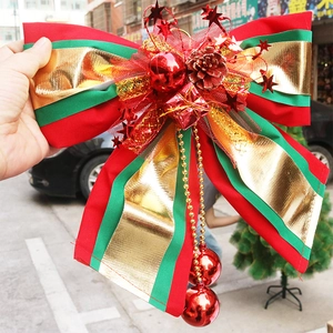 Detailed close-up of a large red, green, and gold Christmas bow with bells and pine cones