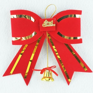 Detail of red velvet Christmas bow featuring golden Merry Christmas lettering and bell