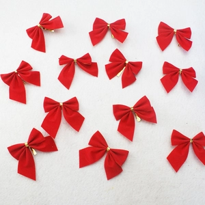 Close-up of small red velvet bows with gold metallic twist ties for Christmas decor