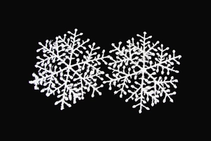 Detail of white Christmas snowflake ornaments with textured finish on black background