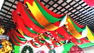 Close-up of three-tier red, green, and gold Merry Christmas ceiling hanging wave flags