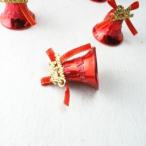 Detail von roten Weihnachtsglocken mit goldenem Schriftzug und Schleife auf weißem Fell