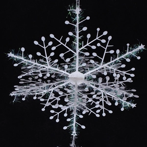 Macro shot of white plastic Christmas snowflake with colorful laser glitter on dark background
