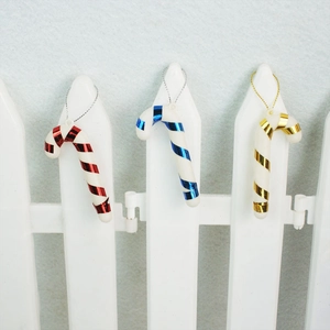 Close-up of red, blue, and gold mini candy cane Christmas tree ornaments with hanging chains