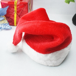 Detail of red plush Christmas hat with soft white pom-pom on festive holiday background