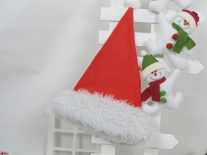 Detail of red Christmas hat with plush trim and LED star on white wooden fence