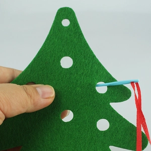 Detail showing a DIY felt Christmas tree kit with a safe plastic needle and red ribbon