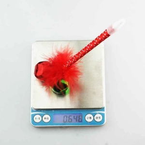 Détail d'un stylo de Noël avec plumes rouges et clochettes sur une balance numérique