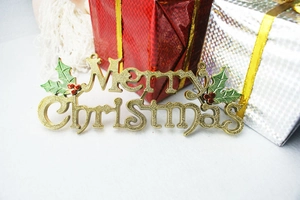 Detail of golden Merry Christmas plaque with holly leaves for Christmas tree decoration
