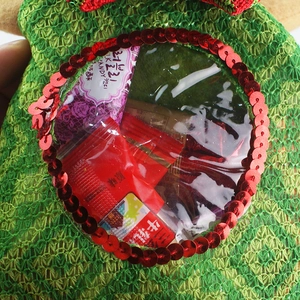 Detail of green knitted Christmas candy bag with transparent window and red sequins