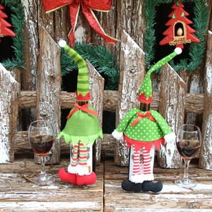 Detailed view of festive elf wine bottle covers on a snowy wooden background