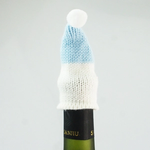 Close-up of blue and white knitted mini hat with pompom on a wine bottle neck