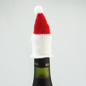 Close-up of red and white knitted Christmas mini hat for wine bottle decoration with pompom