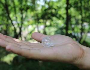 Vista macro di mini sfere trasparenti da 1 cm per decorazioni natalizie fai da te su mano