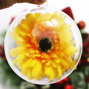 Dettaglio di una pallina di Natale trasparente con un fiore finto giallo all'interno