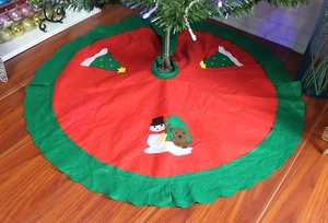 Detail of red Christmas tree skirt with snowman and bear felt patches and wavy edges