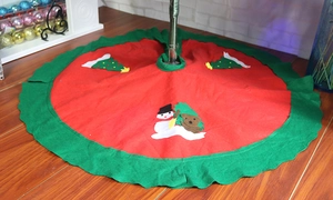 Macro shot of red felt Christmas tree skirt featuring snowmen and green ruffles