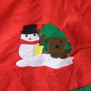 Close-up of red felt Christmas tree skirt featuring snowman and bear applique detail