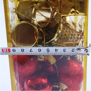 Close-up of a 6cm transparent box with red glitter balls and gold drum ornaments